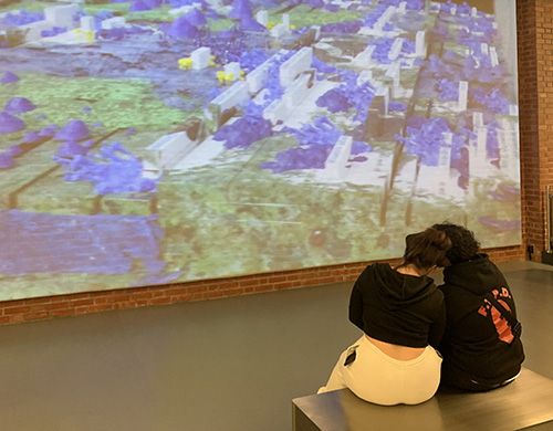 To sitter på en benk og betrakter kunstverket