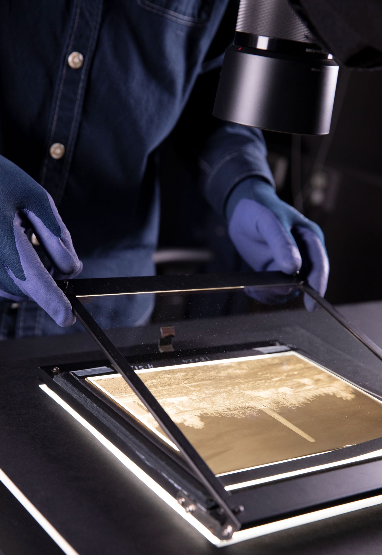 Hender løfter opp en glassflate på et fotografi