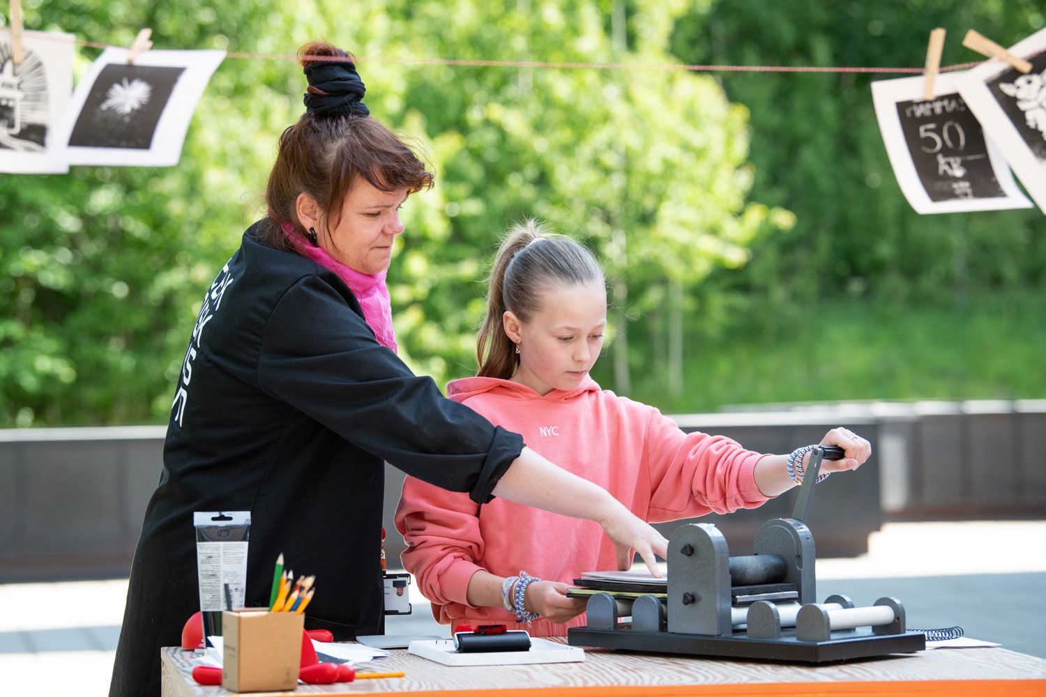 En pedagog og jente lager et linotrykk ute på terrassen.                                                                                                                              