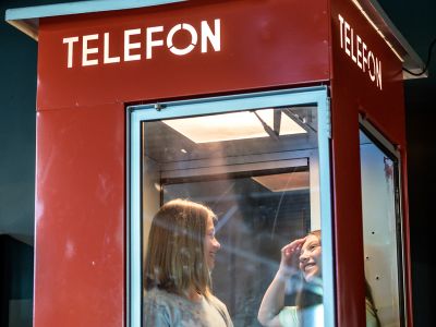 To jenter i en rød telefonkiosk