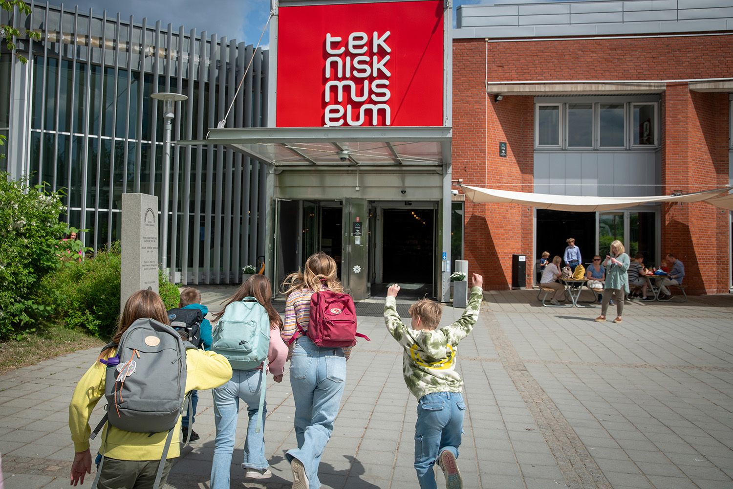 Barn med ryggsekk som løper mot inngangen til Teknisk museum